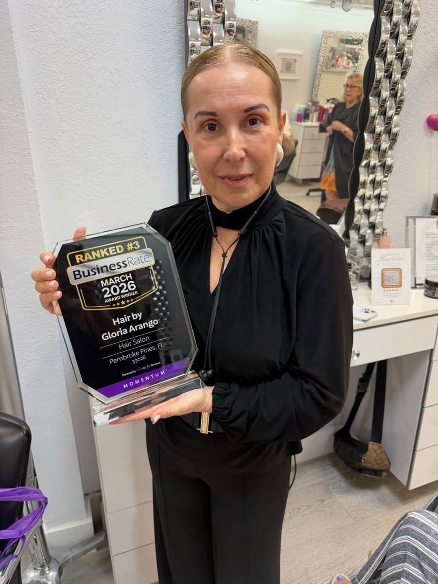 Gloria Arango holding her BusinessRate award in her salon