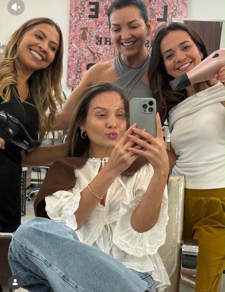 Stylists with a client in a salon mirror